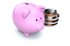 Pink piggy bank with stack of U.S. coins behind isolated on white