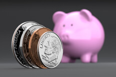 Coins standing on edge U.S. coins standing on edge in foreground with blurred pink piggy bank in background