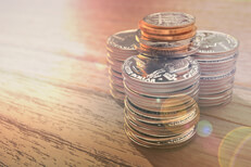 Large stacks of coins flare Three large stacks of shiny quarters with other smaller coins on top with lens flare