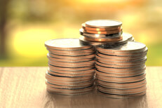 Coins with sunshine Large stacks of U.S. coins on wood table with sunny yard in background outside window