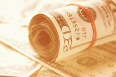 Roll of twenty dollar bills on random stack of bills with bright summer light