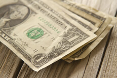 Random stack of dollars on wood planks Angled view of random stack of dollar bills on wood plank background