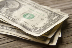 Angled stack of dollars on wood planks Angled view of random stack of dollar bills on wood plank background