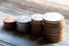 U.S. coins stacked Stacks of pennies, nickels, dimes, and quarters on wood planks in warm morning light