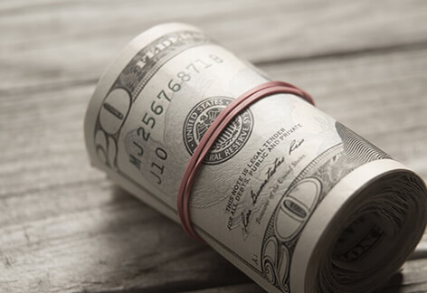 Roll of twenty dollar bills Large roll of twenty dollar bills on wood background