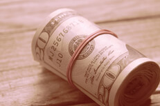 Large roll of twenty dollar bills on wood background with instagram western lighting