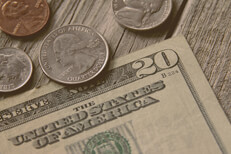 Twenty dollars and 41 cents Single twenty dollar bill with quarter, nickel, penny, and dime on wood background