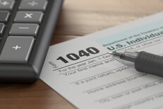 Form 1040 tax calculator Tax form 1040 with ballpoint pen and calculator on wood surface