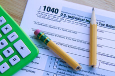 Tax irritation Broken pencil lying on IRS form 1040 on desk with green compact calculator