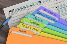Fanned tax folders 1040 form Rainbow tax category folders fanned out on top of IRS form 1040 with ballpoint pen