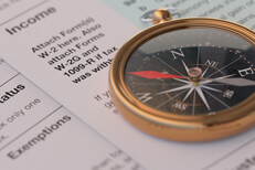 Income tax forms with navigational compass concept for tax help, direction, or advice