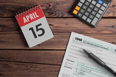 April 15 day planner calendar with calculator and IRS form 1040 on wood background