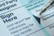 Pen signing 1040 tax form Close view of ballpoint pen signing signature line on 1040 tax form