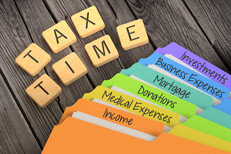 Fanned rainbow-colored manila folders for tax categories with Scrabble letters spelling TAX TIME