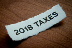 Concept photo of torn piece of paper with 2018 taxes printed text and depth of field blur